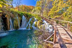 Plitvické jazerá s tyrkysovým vodopádom, zeleň a drevený chodník. Chorvátsko