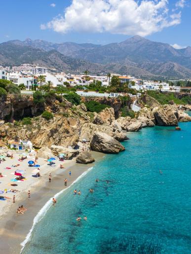 Piesková pláž, tyrkysové more a biele mesto Nerja v Andalúzii.