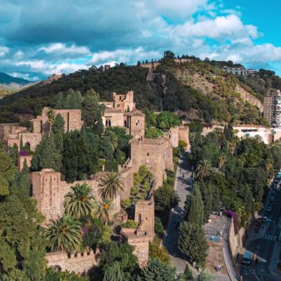 Zelený park a pevnosť Alcazaba počas dňa v Malage.