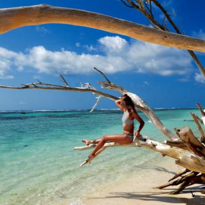 Mladá žena na konári na pláži na Seychelách.