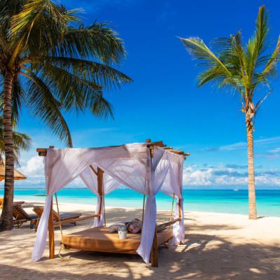 Piesková pláž, palmy a luxusné ležadlo pred hotelom Zuri Zanzibar Hotel & Resort, Zanzibar.