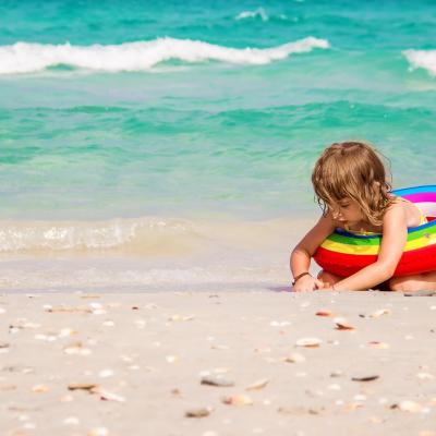 Dieťa hrajúce sa na svetlom piesku pri mori v Tunisku.