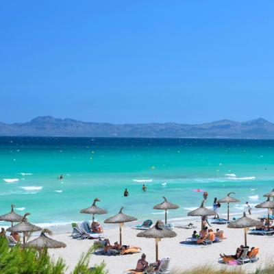 Tyrkysové more, biely piesok a ľudia na pláži v Španielsku.