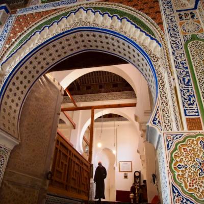 Detailne zdobená mešita a kráčajúci muž.