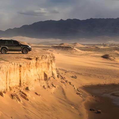 Džíp na okraji púšte počas západu slnka v Mongolsku.