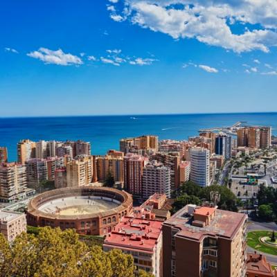 Mesto Malaga s domami, arénou, prístavom a morom počas slnečného dňa.