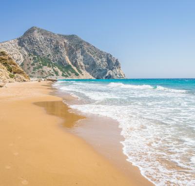Piesočná pláž s vlnami a útesmi v Grécku