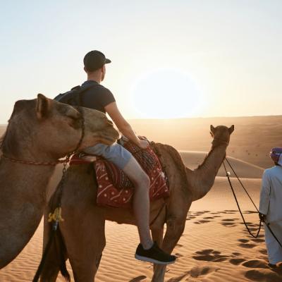 Dovolenkár na ťave s miestnym prechádza púšťou Wahiba sands, Muscat, Omán