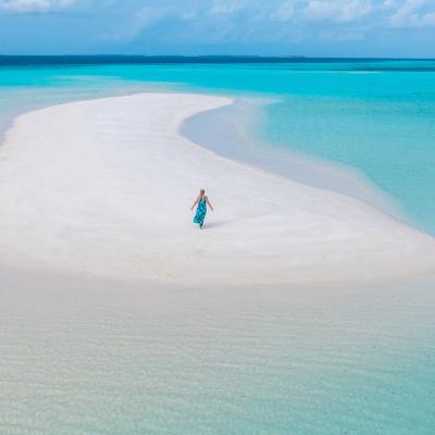 dronový záber na ženu na pláži v maldivskej lagúne