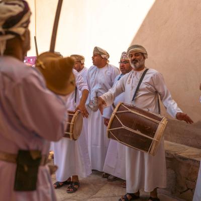 Impozantný hrad Nizwa a miestni obyvatelia v tradičnom odeve dishdasha, Muscat