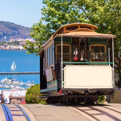 Električka na ulici a oceán s pevnosťou v pozadí.