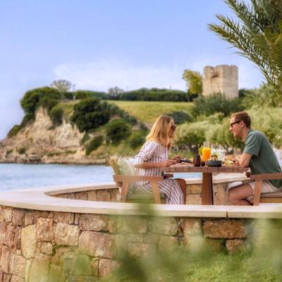 Pár sediaci na terase pri mori na Chalkidiki.