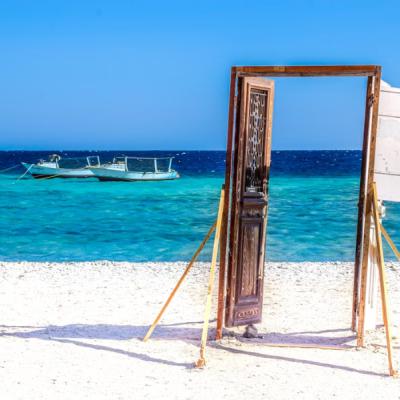 Drevené dvere na pláži a loď na mori v Marsa Alam počas dňa.