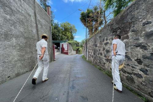 Dva muži na ceste ťahajúci sane v meste Funchal, Madeira.