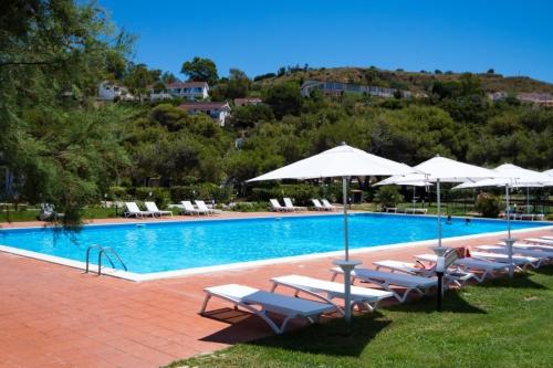 Bazén s lehátkami hotela BV Kalafiorita Resort v pozadí s lesom