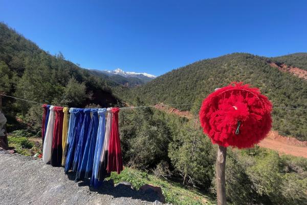 Farebné šatky a zelené svahy so snehom vo Vysokom Atlase v Maroku.