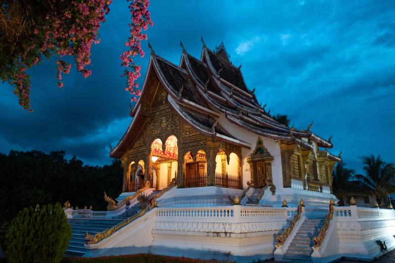 Chrám v Luang Prabang vysvietený pod modrou večernou oblohou v Laose. 
