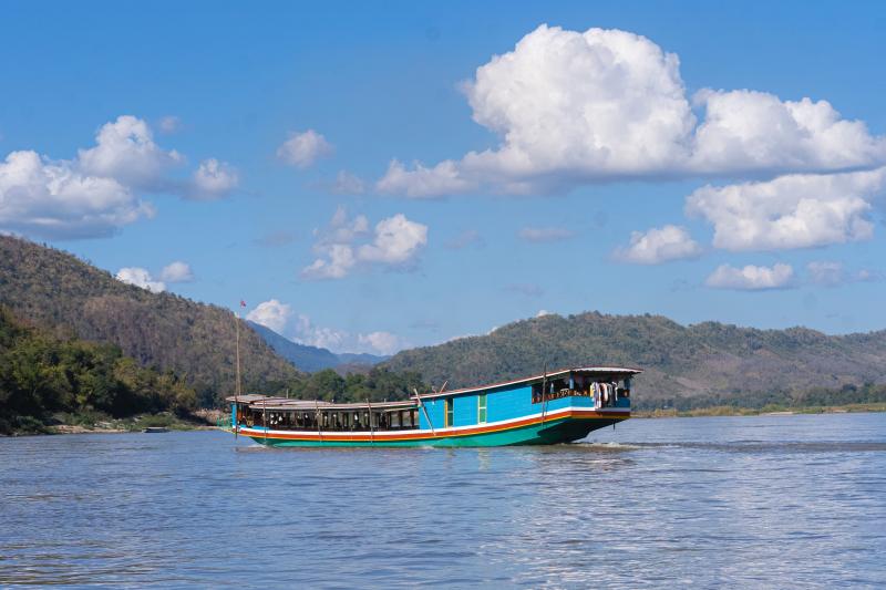 Bujná zeleň, rieka Mekong a farebná loď na cestu ku prírodným krásam Laosu. 
