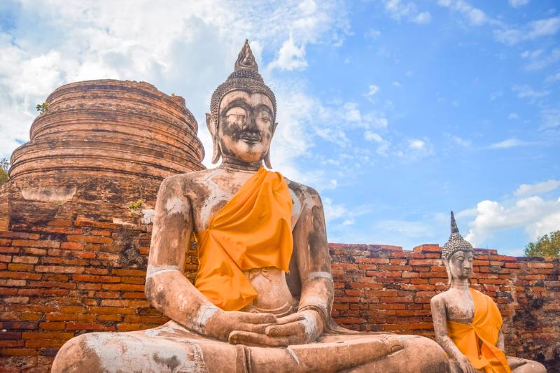 Sediaci Budha pred zbytkami tehlového chrámu v Ayutthayi. Thajsko