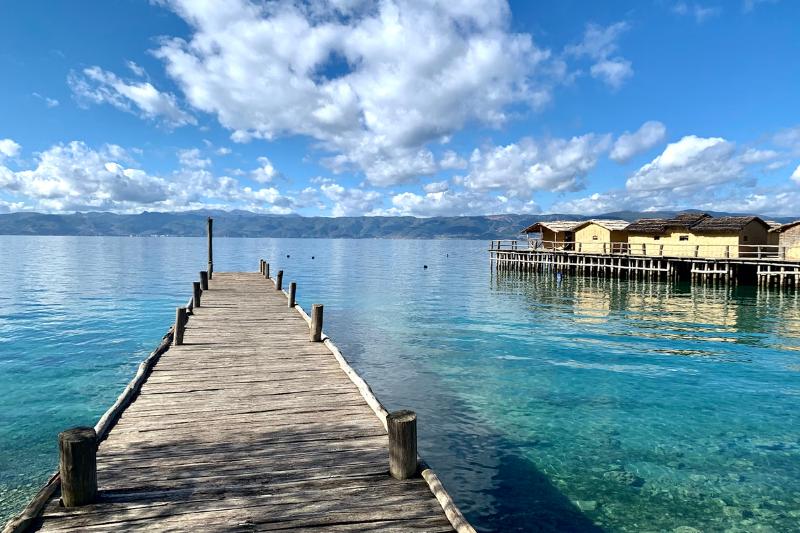 Jazero Ohrid s dreveným mólom a domami na vode.