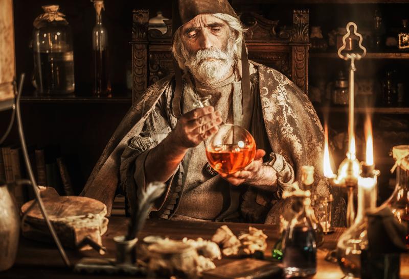 Muž sediaci v laboratóriu pri rôznych flaštičkách.