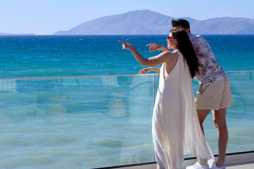 Pár pri sklenom zábradlí pri mori na ostrove Kos.