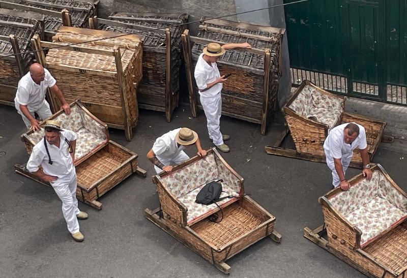 Prútené sane a muži v bielom odeve na Madeire.