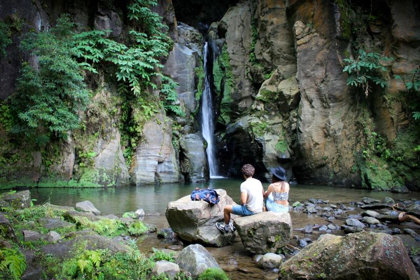 Vodopádo Salto do Cabrito a pár sediaci na skale. Azorské ostrovy.