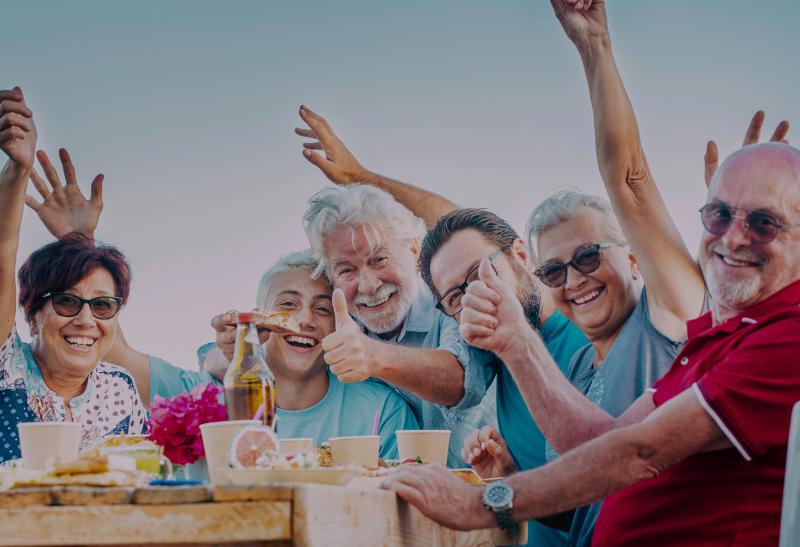 Usmiati ľudia pri stole s jedlom.