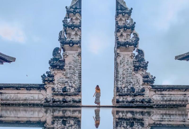 Žena prechádzajúca cez bránu na ostrove Bali.
