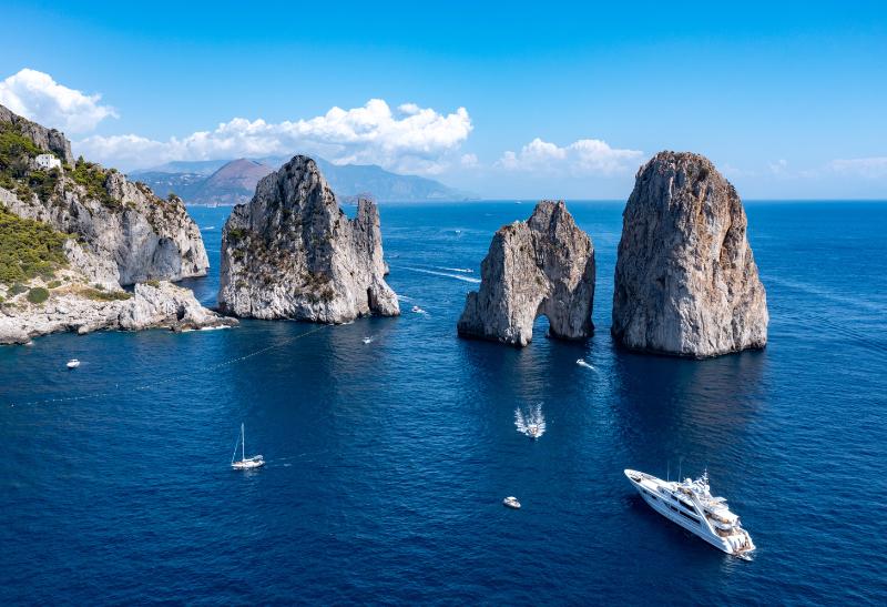 Tri vápencové skaly Faraglioni na Capri a lode.