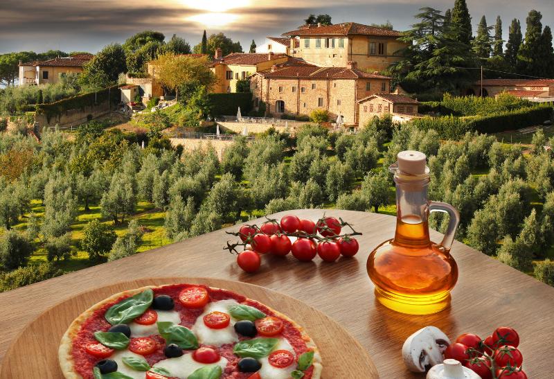 Pizza, paradajky, staré domy a zelené kopce v Toskánsku.
