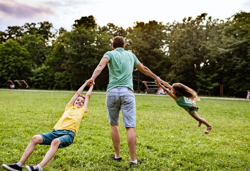 Otec sa točí na tráve so synom a dcérou.