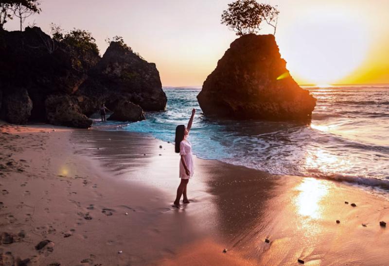 Dievča na pláži pri západe slnka na Bali.
