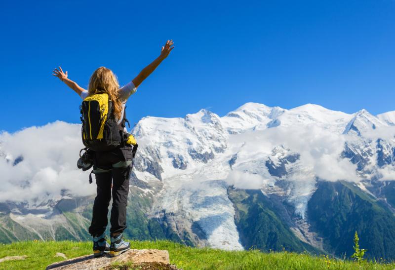 Žena v horách s výhľadom na zasnežené pohorie.