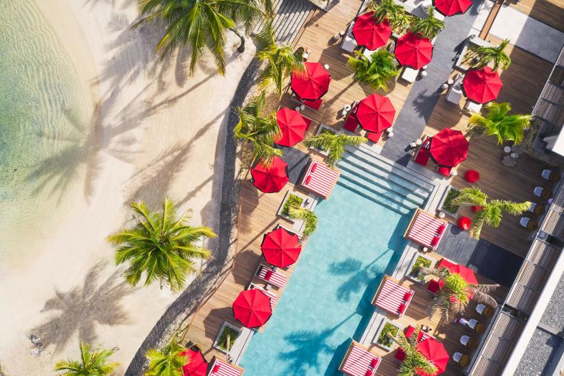 Bazén so slnečníkmi a piesková pláž pred hotelom LUX Grand Baie. Maurícius.