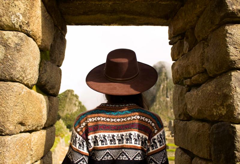 Žena v klobúku v kamennej bráne v Machu Picchu.