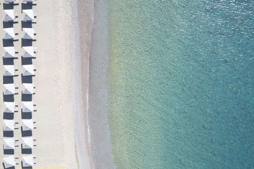 Pláž a biele slnečníky pred hotelom Mayia Exclusive Resort & Spa. Rodos.
