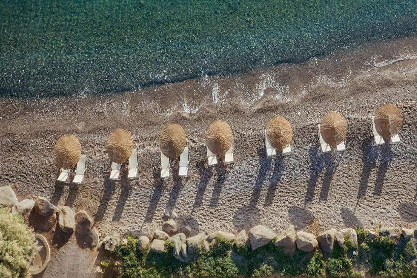 Piesková pláž so slenčníkmi a modré more na ostrove Kos.