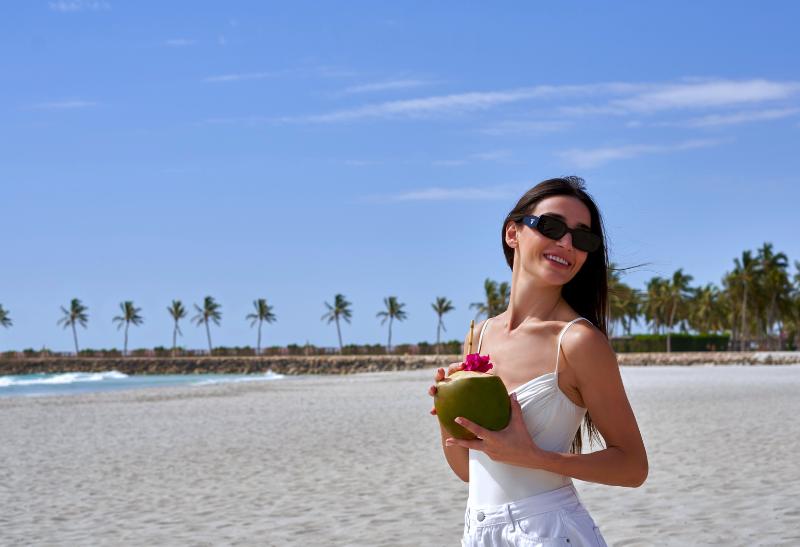 Pláž a žena s kokosom pri mori.