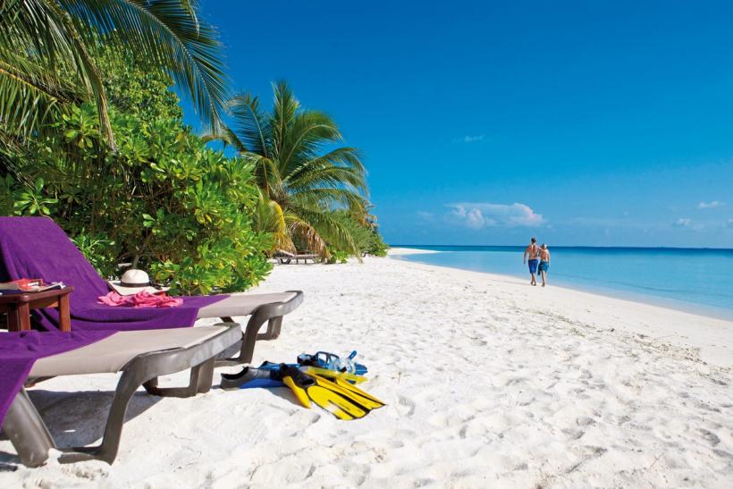 Pár na pieskovej pláži pri mori na Maldivách.