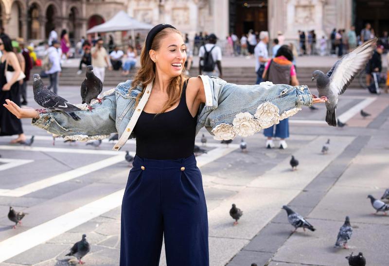 Mladá žena s holubmi pred Duomo v Miláne.