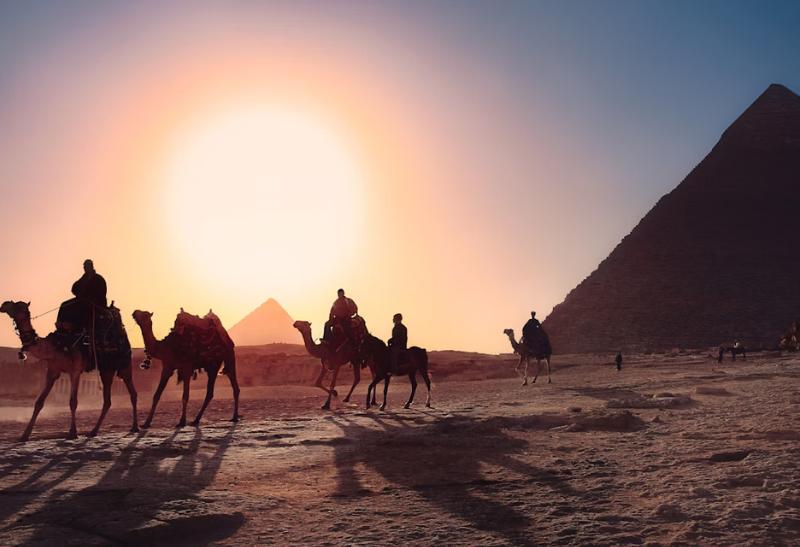 Pyramídy v Gíze a karavána tiav pri západe slnka v Egypte.