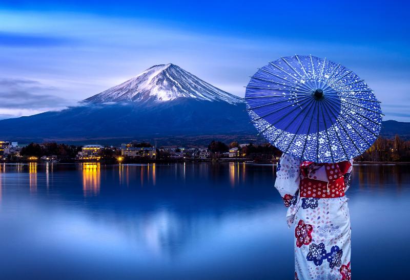 Japonská žena v kimone a s dáždnikom pred sopokou Fudži v Japonsku.