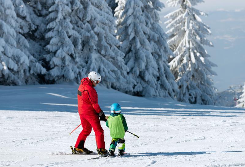 Inštruktor lyžovania učí dieťa lyžovať na svahu.