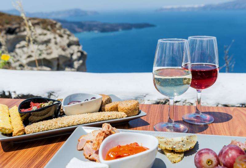 Jedlo a víno na stole s výhľadom na more v Grécku.