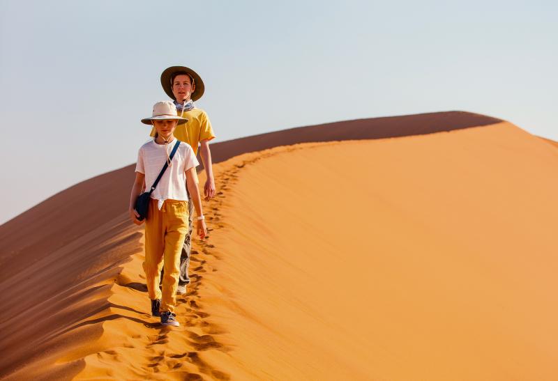 Dve deti kráčajú po púštnej dune.