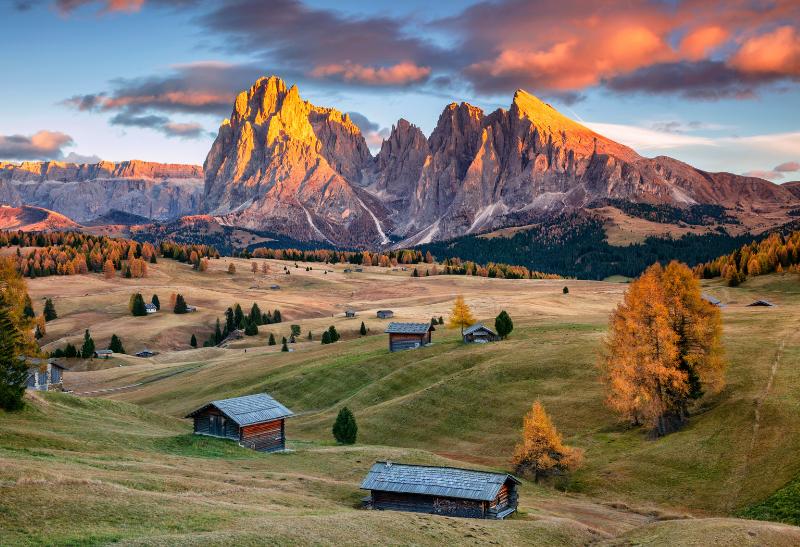 Drevené domy, kopce a vysoké štíty v Dolomitoch.
