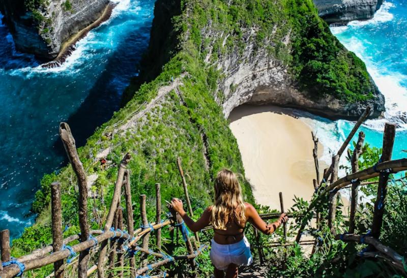 Dievčina schádzajúca dolu po schodoch na pláž na Bali.