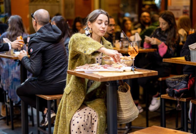 Hostia za stolom pijú a jedia v Bologni.